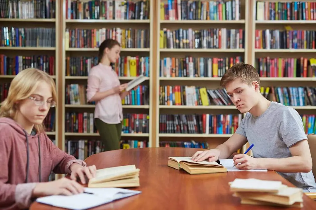Teenage guy rewriting text from book in library