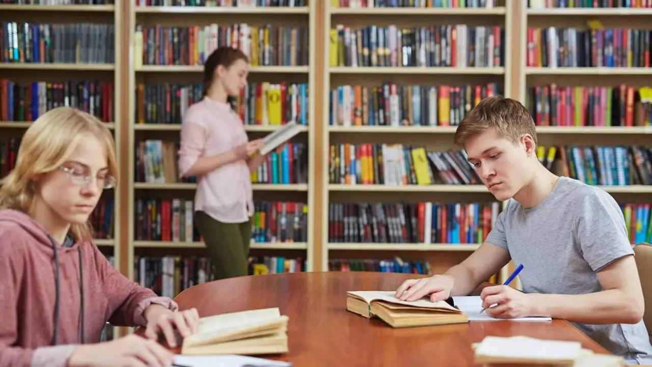 Teenage guy rewriting text from book in library